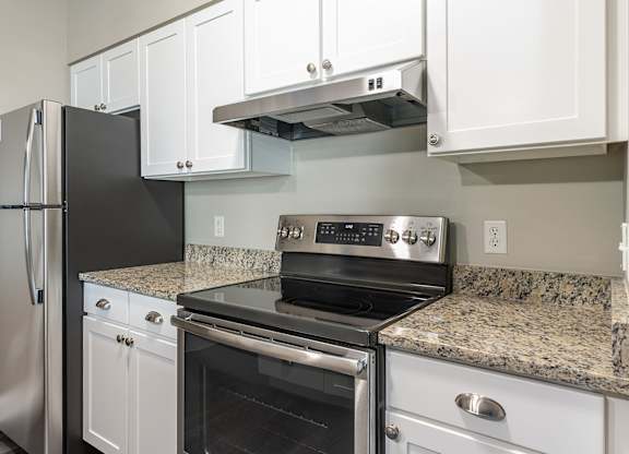 Parkside Commons apartment kitchen with refrigerator next to a black stove in a kitchen.