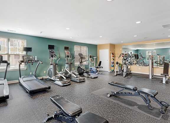 A gym with treadmills, exercise bikes, and other equipment at Parkside Commons