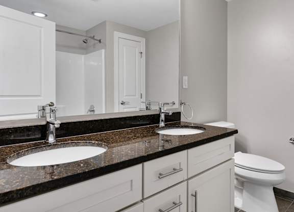 A bathroom with a sink, toilet, and mirror.