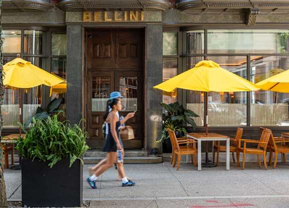 A woman is walking on the street in front of the Exchange Building.