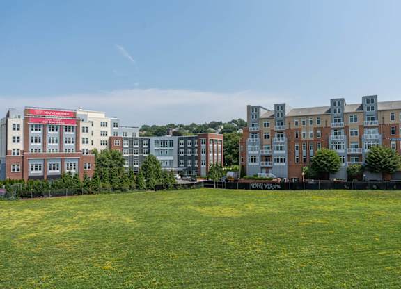 A grassy field in front of apartment buildings.