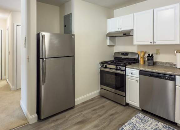 A kitchen with a refrigerator, oven, and stove.