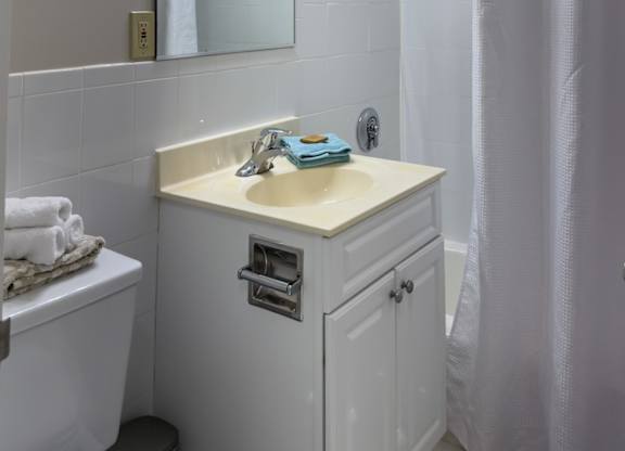 A white bathroom with a sink, toilet, and shower.