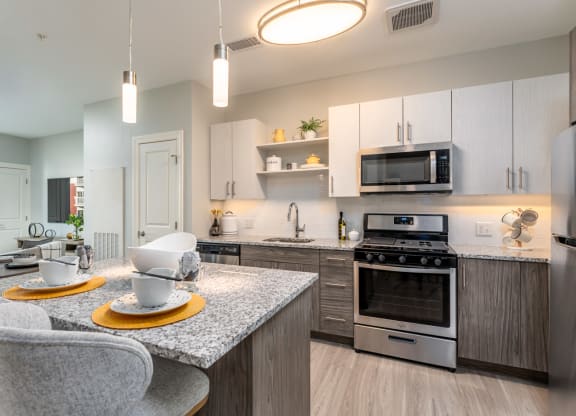 One bedroom model apartment with overhead and undercabinet lighting, granite countertop, kitchen island, stainless appliances