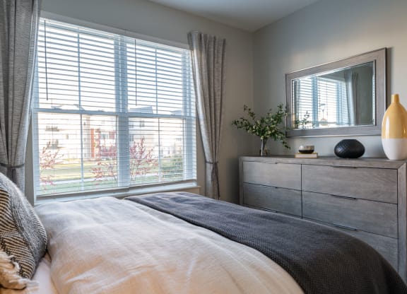 Model apartment bedroom with large windows overlooking courtyard