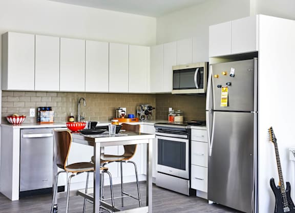 A kitchen with a refrigerator, oven, and microwave, model apartment