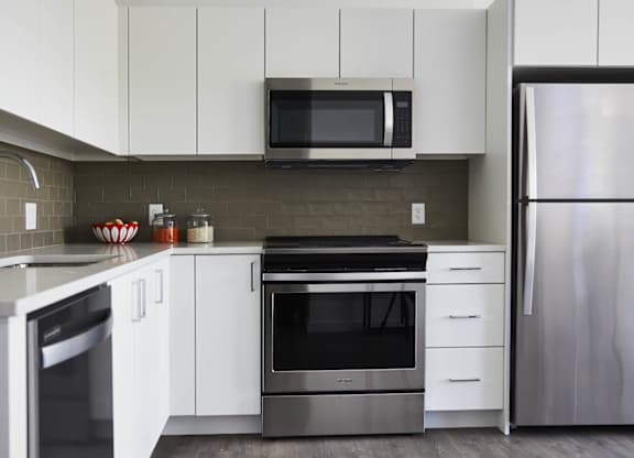 A modern kitchen with a refrigerator, oven, and microwave, vacant apartment.