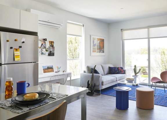 A modern kitchen with a dining table and chairs, large windows/balcony model apartment