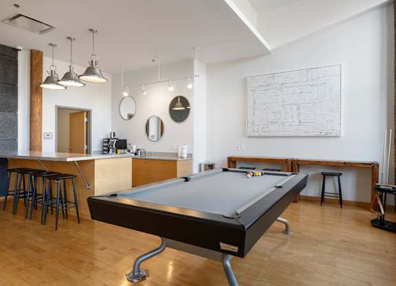 A pool table is in the middle of a room with a bar and a ping pong table.