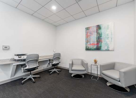 A white room with a grey carpet and a painting on the wall.