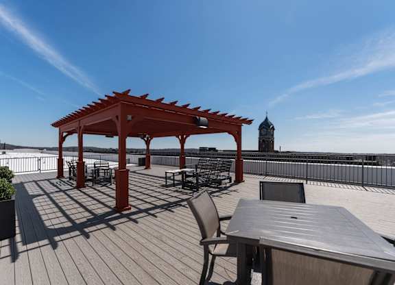 A wooden gazebo with a table and chairs is set up on a wooden deck.