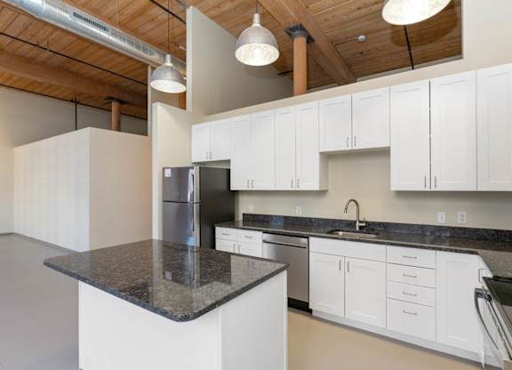 A kitchen with white cabinets and a black countertop.