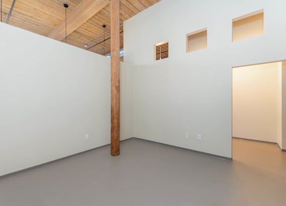 A room with a white wall and a wooden beam on the ceiling.