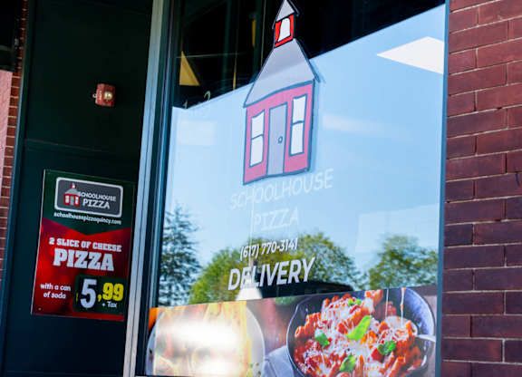 A pizza advertisement on a window with a red house icon and a phone number.