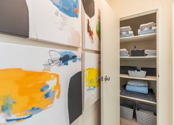 a closet with paintings on the wall and shelves