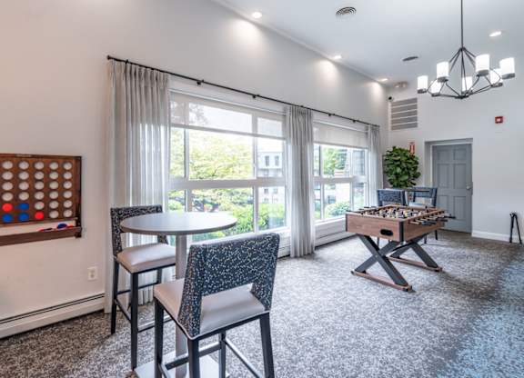 a living room with a game table and chairs and a window