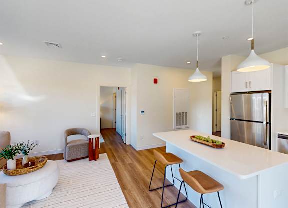 A kitchen with a white counter and wooden chairs.