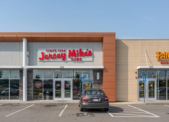A car is parked in front of a store with a red and white sign that says