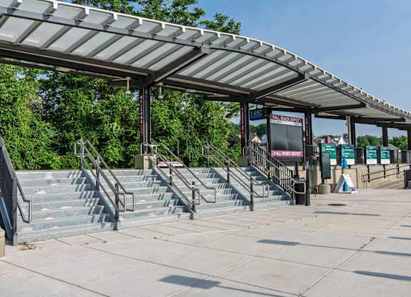 Wide granite steps and glass canopy at the entrance plaza of Fall River Depot commuter-rail station.