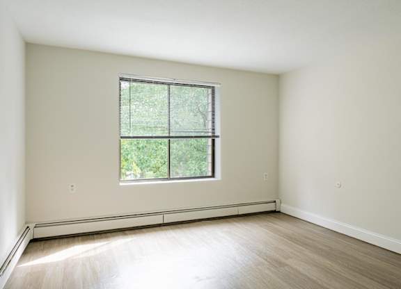a bedroom with hardwood floors and a large window
