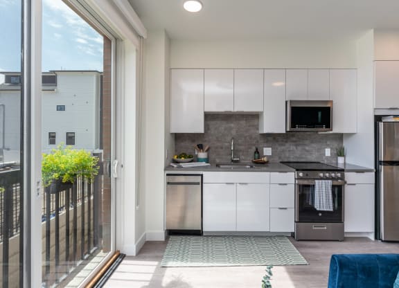a kitchen with white cabinets and stainless steel appliances and a sliding glass door that leads to a at Union 346, Massachusetts, 02143