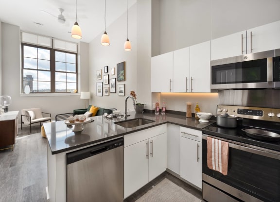 a kitchen with a large granite counter top and a sink, stainless appliances and an electric range