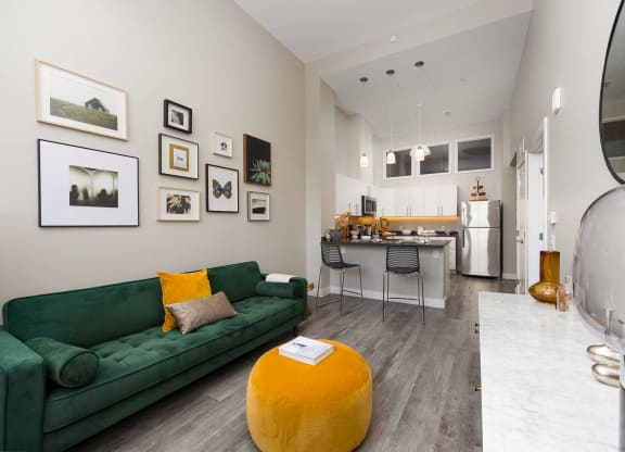 a living room with a green couch and a kitchen in the background