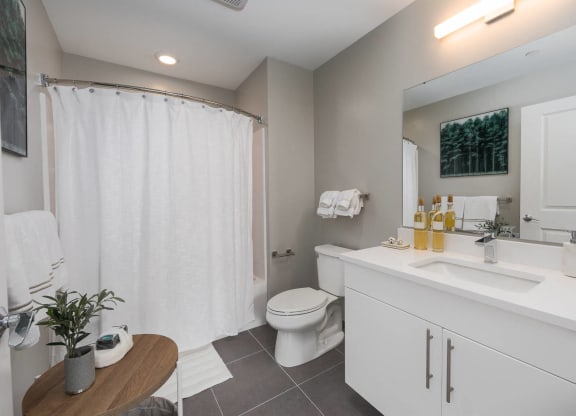 a bathroom with a sink toilet and a shower large vanity bright cabinets