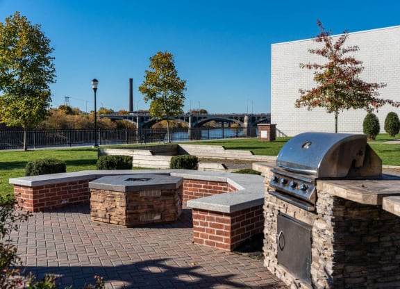 a patio with a barbecue grill and benches with views of the river