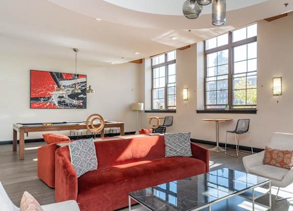The community room at building 240 with a red couch, large windows, pool table