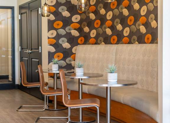 a seating area with two tables and a couch and a wall with a patterned wallpaper, lounge area