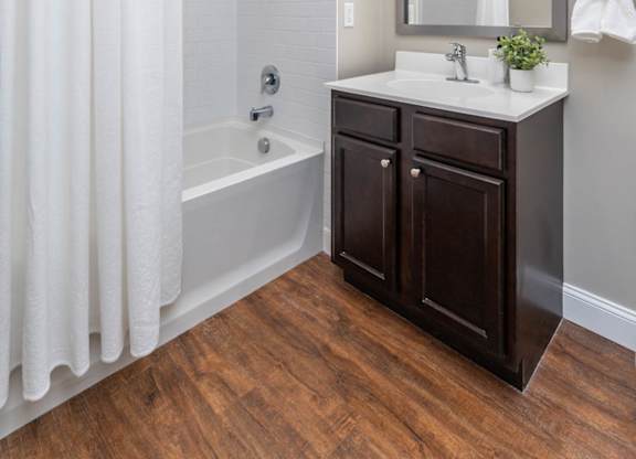 A white shower curtain hangs over a white bathtub in a bathroom.