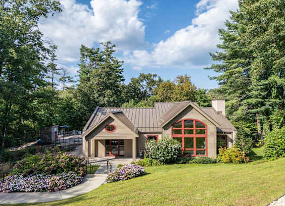the front of a house with a lawn and trees