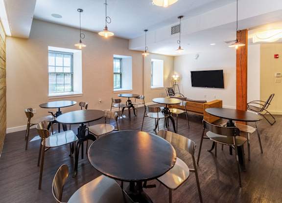 a dining room with tables and chairs and a tvat Ames Shovel Works Apartments, Massachusetts, 02356