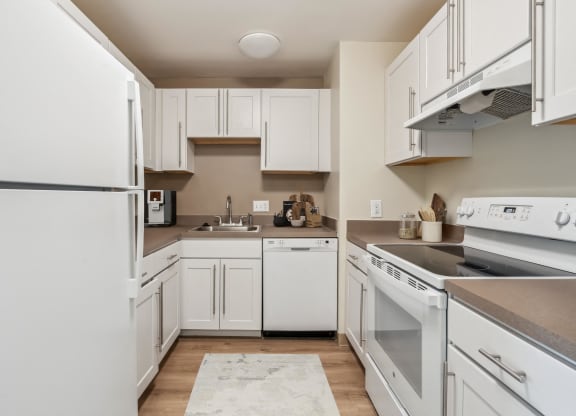 a kitchen with white cabinets and appliances and a sink at Chapman House, E. Boston, MA