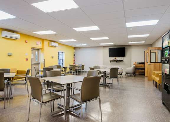 A room with tables and chairs and a television on the wall at Branchwood Towers, Clinton