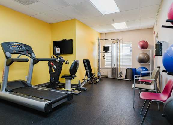 A gym room with a treadmill, exercise balls, and weights at Branchwood Towers, Clinton