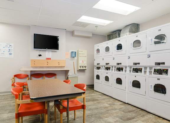 A room with a table, chairs, and a wall of ovens at Branchwood Towers, Clinton