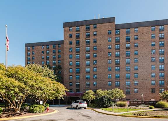 A large brick building with a flag on the left side and a car parked in front at Branchwood Towers, Clinton