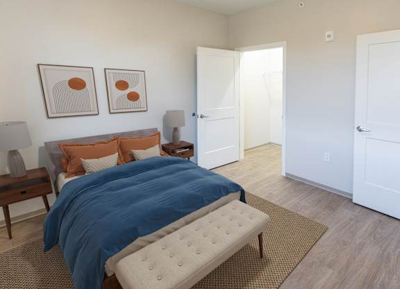 A bedroom with a bed, nightstand, and two framed pictures on the wall  at 35 Broadway Apartments, Menands, New York