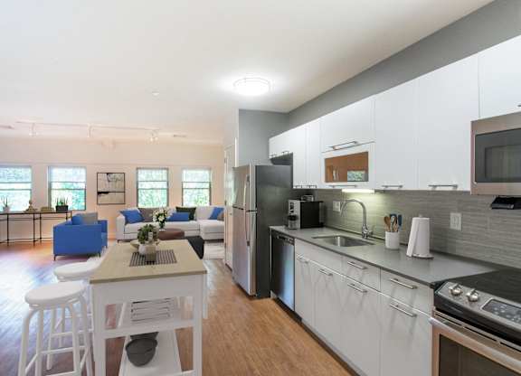 a kitchen and living room with white cabinets and a table and chairsat Ames Shovel Works Apartments, Massachusetts, 02356