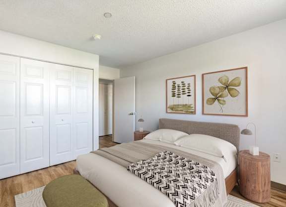 A bedroom with a bed, a green ottoman, and a wooden side table at Brewery Square Apartments, Connecticut