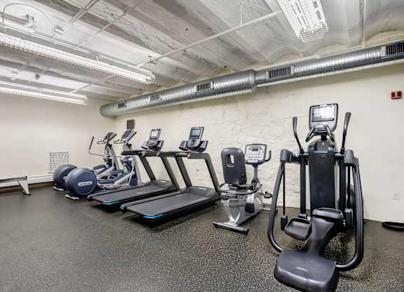 A gym with treadmills, elliptical machines, and other exercise equipment at Brewery Square Apartments, New Haven , CT