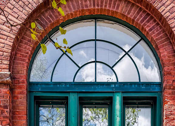 A  glass window with green trim and a brick wall at Brewery Square Apartments, New Haven  06513