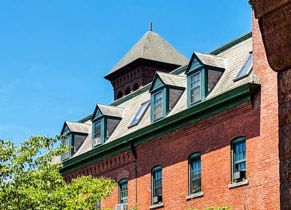 A red brick building with green trim and a steeply pitched roof at Brewery Square Apartments, New Haven , Connecticut