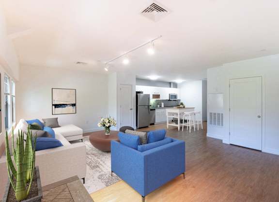a living room with couches and a table with a kitchen in the backgroundat Ames Shovel Works Apartments, North Easton, MA