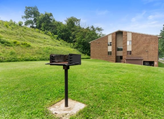 a grill on a pole in the grass in front of a brick building  at Belvedere Acres Apartments, Washington, PA, 15301