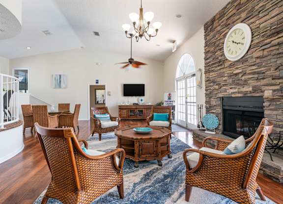 A living room with a fireplace and a large clock on the wall Fishermans Landing Apartments in Ormond Beach, FL.