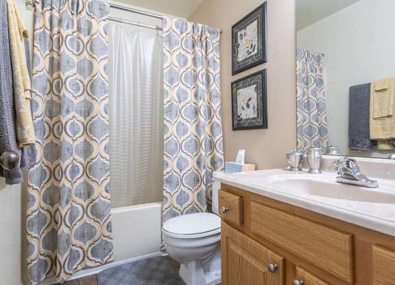 A bathroom with a toilet, sink, and shower curtain Fishermans Landing Apartments in Ormond Beach, FL.