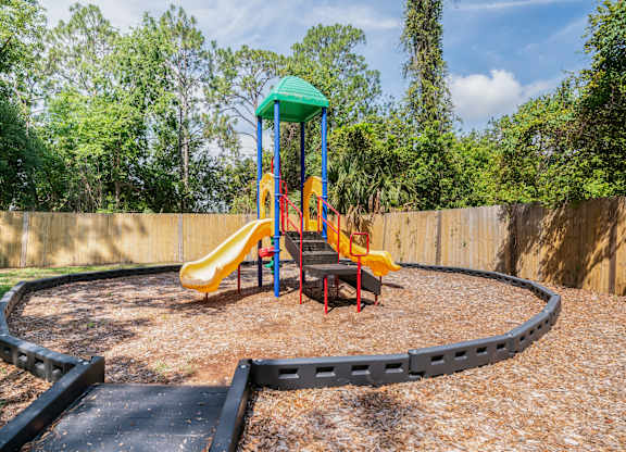 A playground with a yellow slide and a green roof Fishermans Landing Apartments in Ormond Beach, FL.